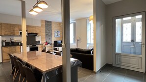 Une cuisine moderne avec un coin repas, un espace de vie doté d’un canapé et une vue sur l’extérieur grâce à une porte vitrée.