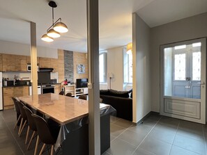 Una cocina moderna con comedor, una sala de estar con sofá y vistas a través de un ventanal.