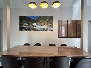 Un salón de conferencias con una mesa de madera, seis sillas y un cuadro grande de un río.