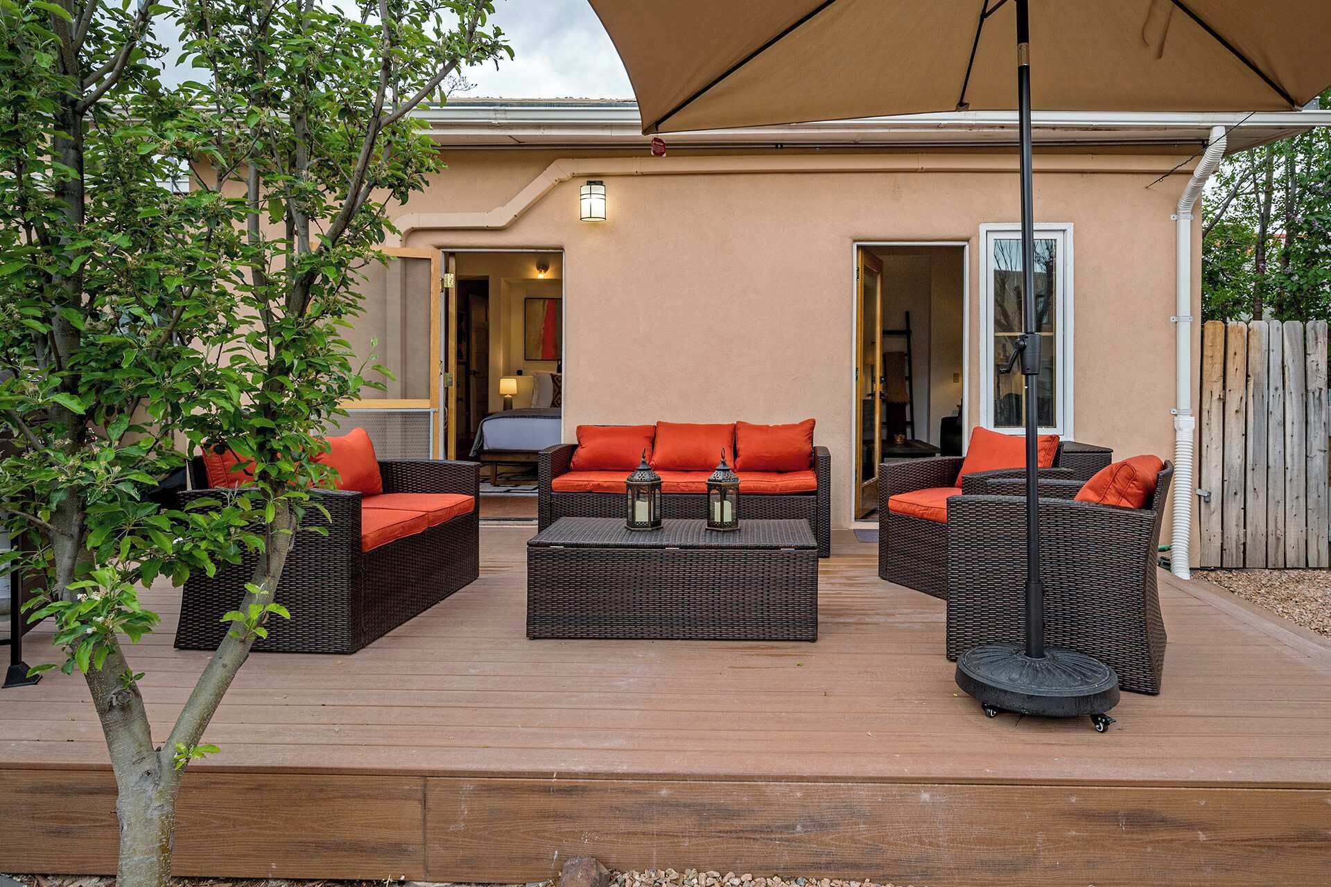 Un espace extérieur aménagé en terrasse, avec des meubles en osier, des coussins rouges et un grand parasol.