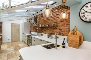 Enjoy cooking in this well-equipped kitchen with a brick wall backdrop, stainless steel appliances, and a pendant light.