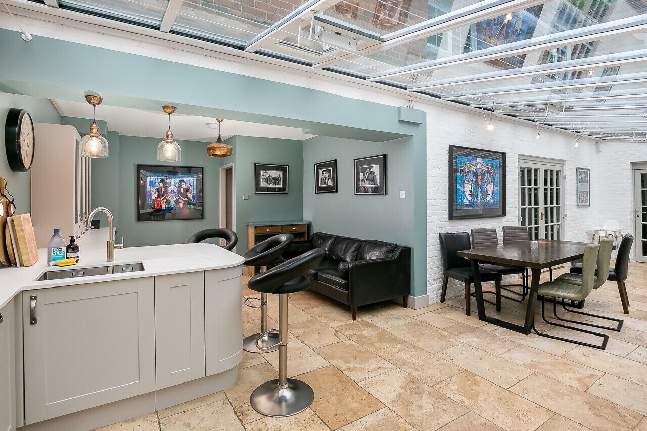 A modern kitchen with a built-in island, bar stools, and a dining area with a table and chairs.