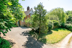 Situated in a suburban setting, this two-story house features a charming pitched roof and a gated entrance.