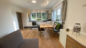 A modern kitchen with a dining area, a sofa, and a small table with a decorative item.