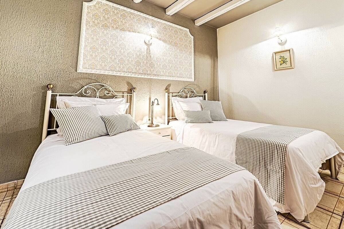 A hotel room with two beds, a large decorative wall piece, and a small framed picture on the wall.