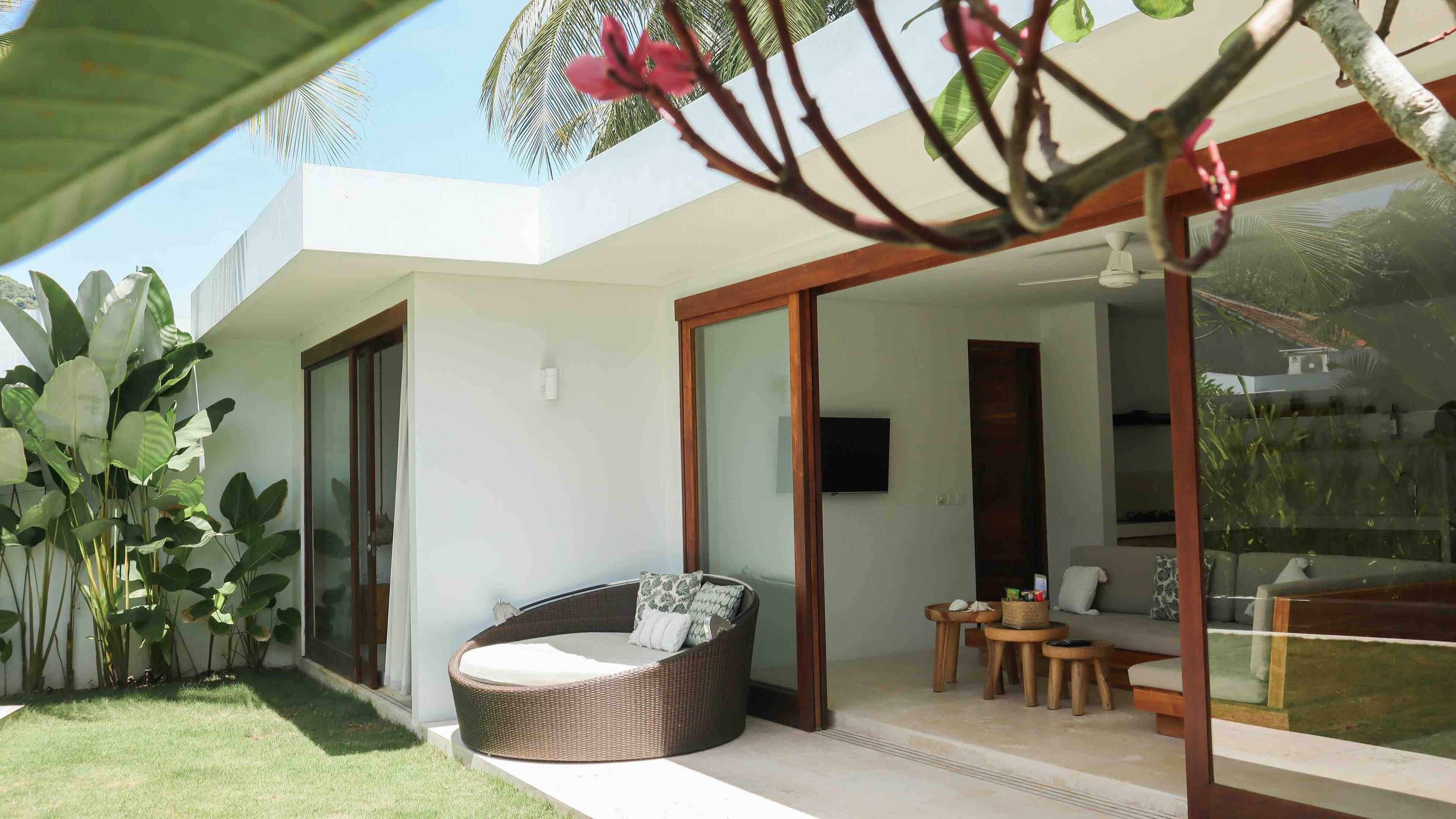 A modern outdoor living area with a wicker sofa, a small table, and a glass door leading to a balcony.