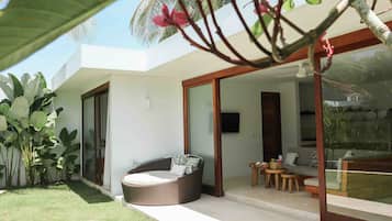 A modern outdoor living area with a wicker sofa, a small table, and a glass door leading to a balcony.