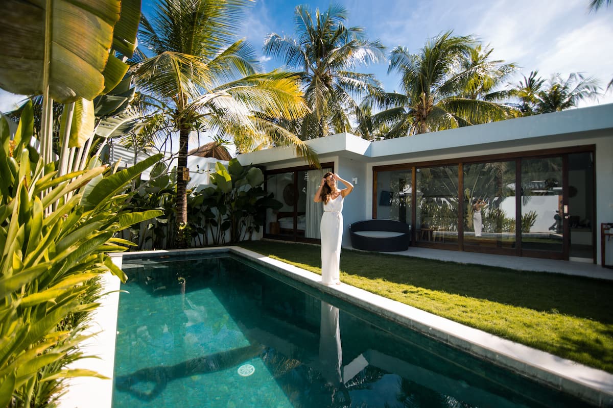 A modern house with a swimming pool surrounded by tropical plants.
