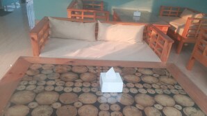 Ein Zimmer mit einem hölzernen Bett, einer Holzbank und einem Glastisch mit Holzscheiten.
