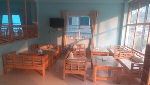 Ein Zimmer mit Holzmöbeln, darunter Sofas und Tische, die um ein zentrales Fenster angeordnet sind.