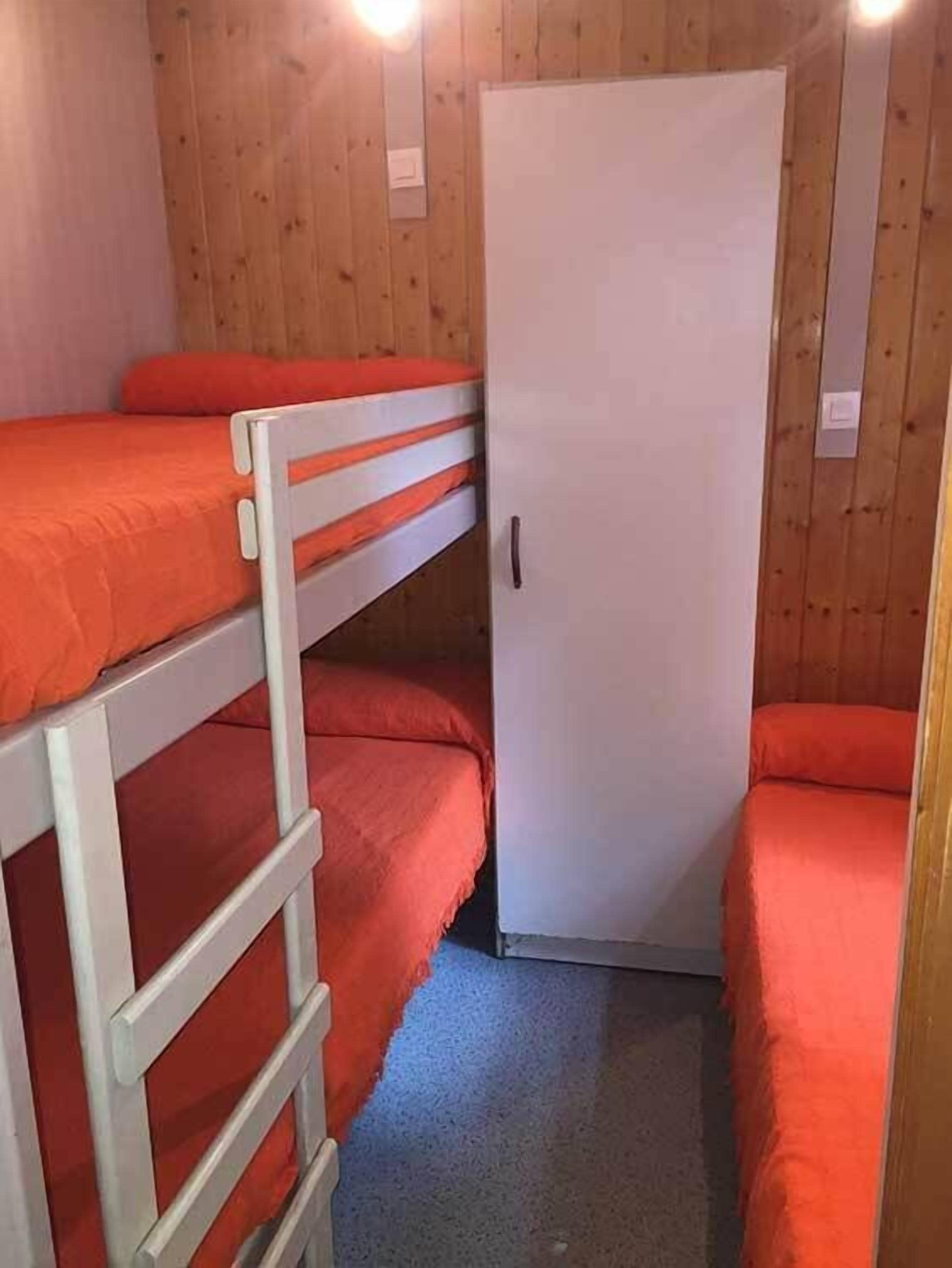 Une chambre avec un lit superposé, une porte blanche et des murs en bois.