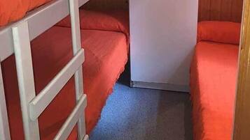 Une chambre avec un lit superposé, une porte blanche et des murs en bois.