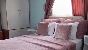 A bedroom with a bed, a wardrobe, a nightstand, and a window with curtains. - Vacation Home "Marilidia House" with 2 Balconies, Shared Terrace & Wi-Fi (Kastelli)