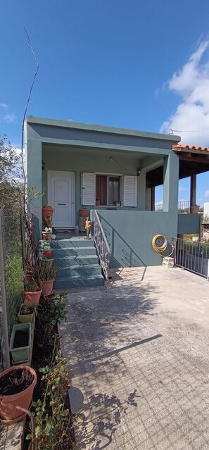 A building with a light blue exterior, a white door, and a small porch with steps leading to a balcony.