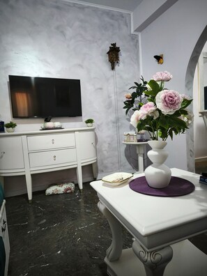 A modern bathroom with a white vanity, a black marble floor, a large mirror, and a wall-mounted TV.