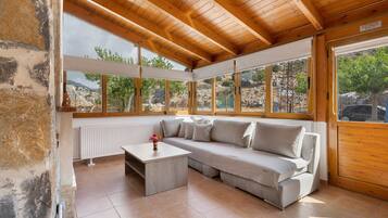 Une pièce avec un plafond en bois, une grande fenêtre, un canapé, une petite table et un radiateur.