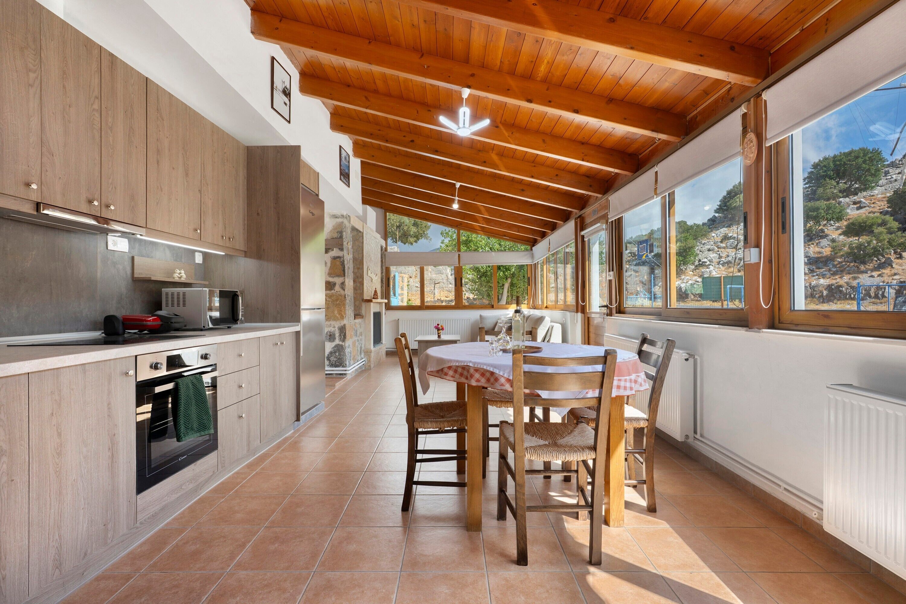 Une cuisine avec des meubles en bois, un four encastré et un coin repas comprenant une table et des chaises.