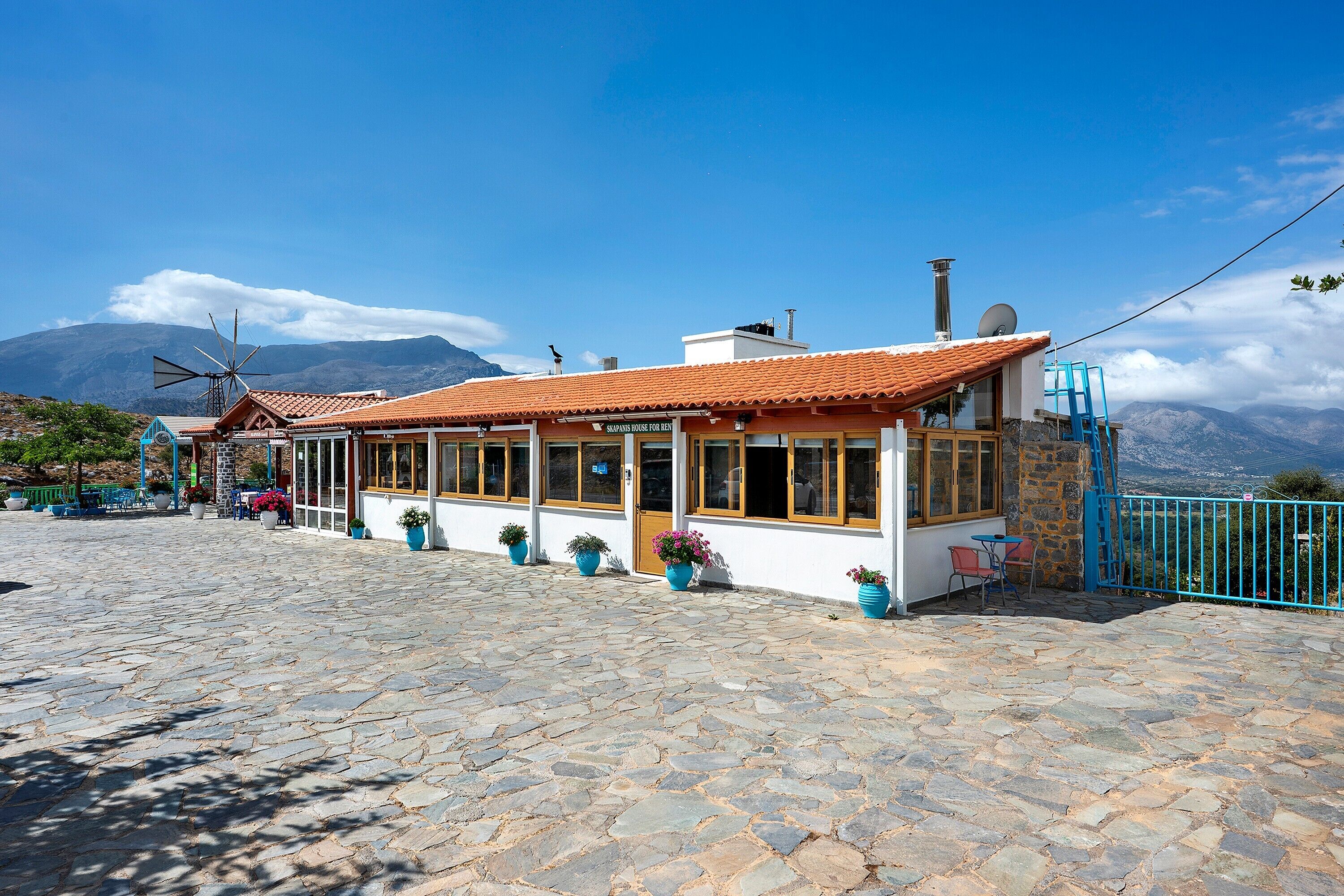 Un bâtiment à deux étages, doté d’un toit en tuiles, de grandes fenêtres et d’une façade en pierre.