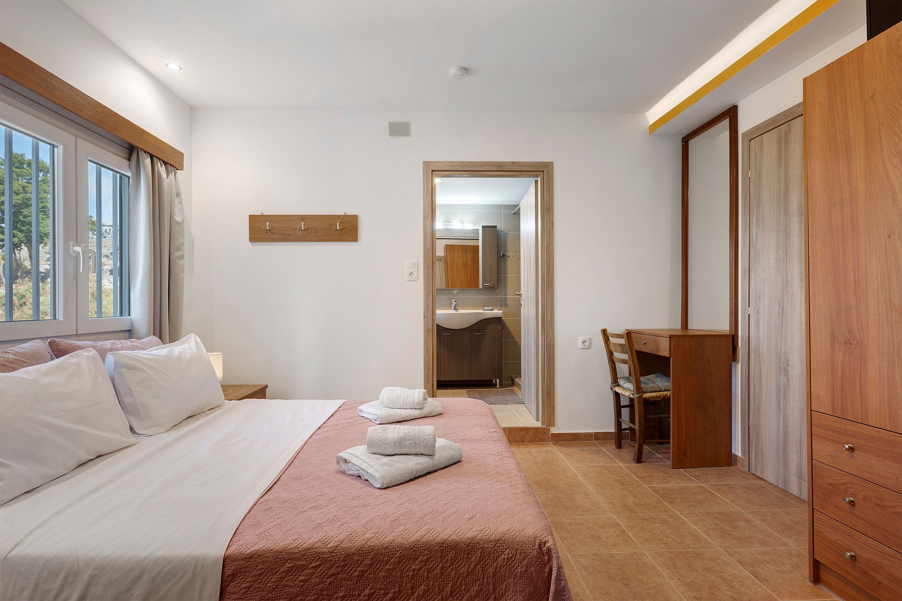 Une chambre d’hôtel avec un lit, un bureau, une chaise et une armoire.