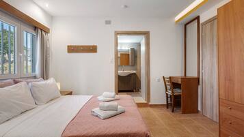 Une chambre d’hôtel avec un lit, un bureau, une chaise et une armoire.