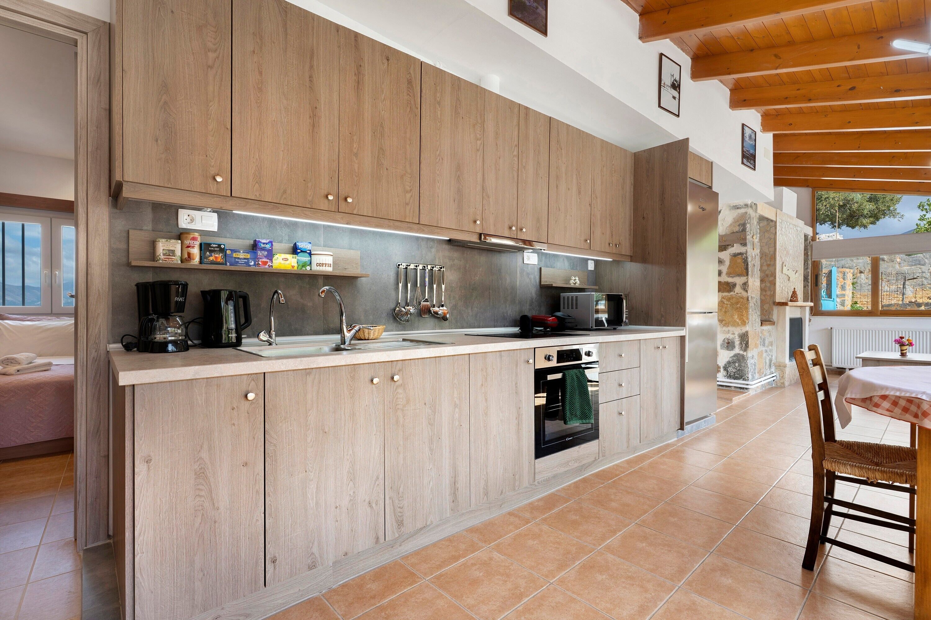 Una cocina moderna con armarios de madera, horno empotrado y comedor con mesa y sillas.