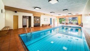 Ein Schwimmbad mit Fliesenboden, einer Holzbank und einer Tür zu einem anderen Raum.