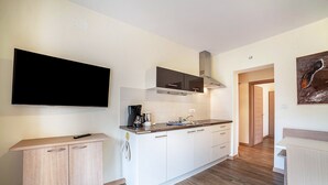 A modern kitchen with a flat-screen TV, wooden cabinets, a coffee machine, and a microwave. - Apartment 'Mignon D' with Mountain View, Shared Garden and Wi-Fi (Riffian)