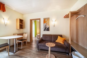 Ein modernes Wohnzimmer mit einer Couch, einem runden Tisch, einer Holzkommode und einem Essbereich.