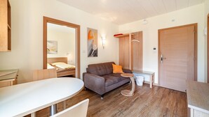 A modern room with a wooden floor, a sofa, a round table, a bed, and a wardrobe. - Apartment 'Mignon C' with Mountain View, Shared Garden and Wi-Fi (Riffian)