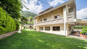 A two-story building with a well-maintained lawn, outdoor seating, and a mountain backdrop. - Apartment 'Mignon C' with Mountain View, Shared Garden and Wi-Fi (Riffian)