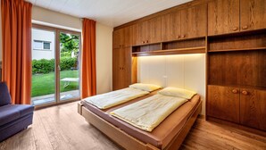 A bedroom with a bed, a chair, wooden cabinets, and a sliding glass door to the outside. - Apartment 'Mignon B' with Mountain View, Shared Garden and Wi-Fi (Riffian)