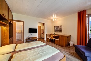 A hotel room with two beds, a desk, a chair, a TV, and a window with curtains.