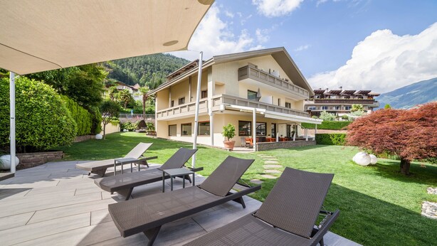 A hotel with a patio area featuring sun loungers, a covered seating area, and a mountain backdrop. - Apartment 'Mignon B' with Mountain View, Shared Garden and Wi-Fi (Riffian)