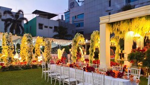 An outdoor event space with white chairs and tables, decorated with floral arrangements and string lights. - Amalia Hotel Lampung (Bandar Lampung)