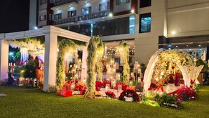 A hotel entrance with a well-lit, decorated facade, a balcony with railings, and a grassy area in front. - Amalia Hotel Lampung (Bandar Lampung)