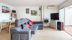 Ein modernes Wohnzimmer mit einem grauen Ecksofa, einem Fernseher, einem Bücherregal und einem Gemälde an der Wand.
