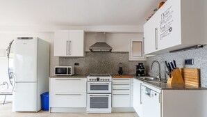 Eine moderne Küche mit weißen Schränken, einem Backofen, einer Mikrowelle und einem Spülbecken.