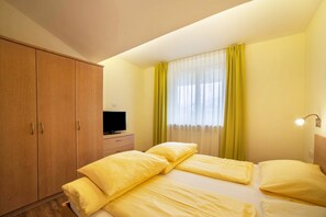 A hotel room with a bed, a television on a dresser, a wardrobe, and a window with curtains. - Holiday Apartment "Mignon 11" with Mountain View, Shared Heated Indoor Pool & Wi-Fi (Riffian)