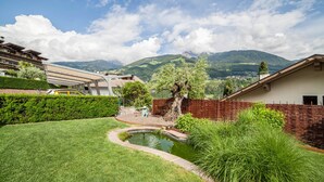 Zona residencial con un estanque, vegetación y montañas al fondo.