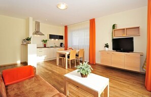 A modern living room with a sofa, a coffee table, a TV, and a dining area with chairs and a table.