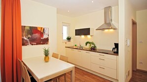 Una cocina compacta con comedor, televisor sobre la encimera y una campana extractora moderna.