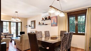 Un coin repas avec une table en verre, des chaises à motifs zébrés et un lustre moderne.