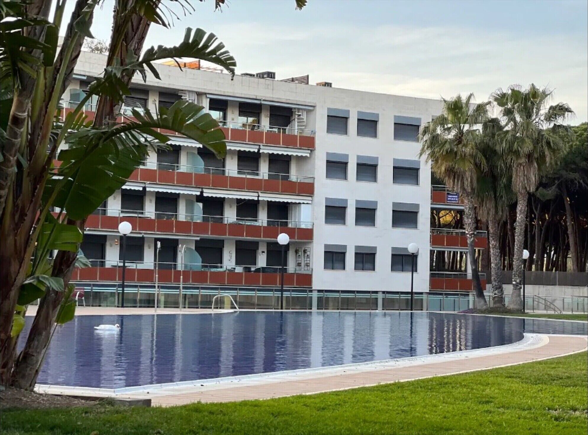A multi-story building with a swimming pool in front.