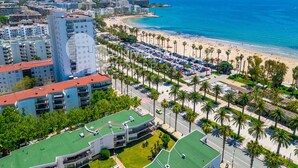 A coastal cityscape with a beachfront, palm-lined promenade, and high-rise buildings. - UHC RODAS 2-bedroom Apartment with AirCon (Salou)