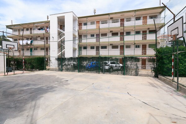 A multi-story residential building with a basketball court in front. - Central, cozy, and with pool 082 SAYONARA (Salou)