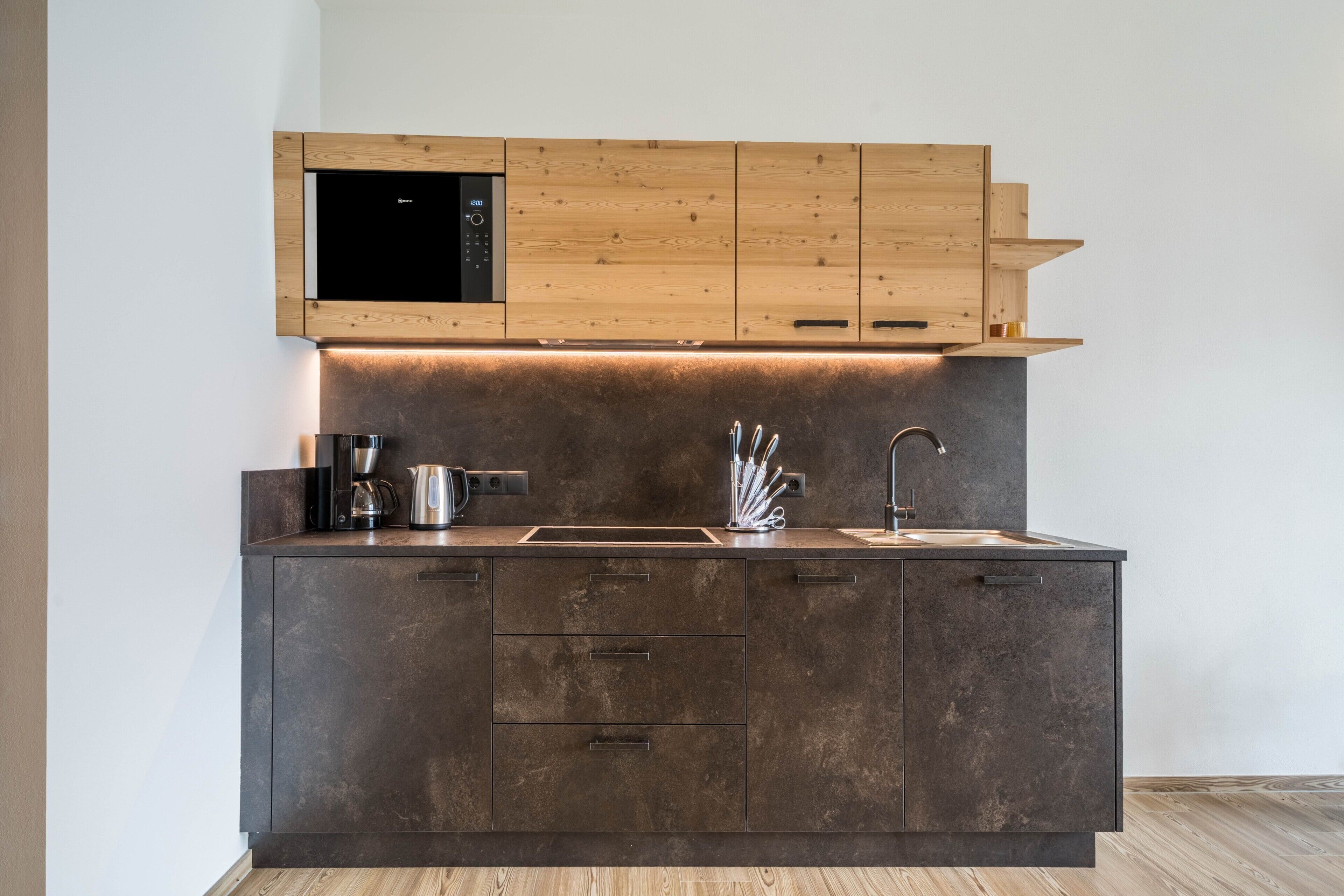 Eine moderne Küche mit integriertem Mikrowellenherd, Edelstahlgeräten und Holzschränken.