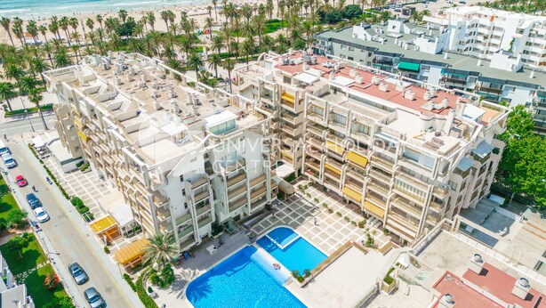A multi-story hotel with a rooftop pool, located near a beach with palm trees and a marina. - UHC NOVELTY APARTMENTS 144 (Salou)