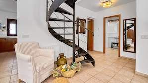 Un escalier en colimaçon dans un intérieur moderne, avec une chaise et un vase de fleurs.
