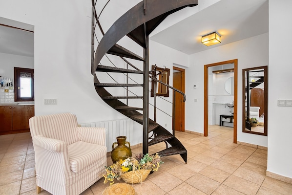 Eine Wendeltreppe in einem modernen Innenraum, mit einem Sessel und einem Blumenarrangement.
