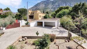 Un barrio residencial con una casa, un camino de entrada pavimentado y una montaña al fondo.